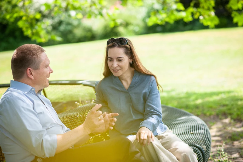 Zwei personen sitzen draußen und unterhalten sich