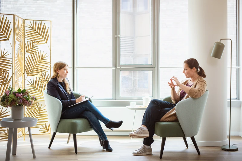 Therapeutin spricht mit Patientin in einem hellen Raum.