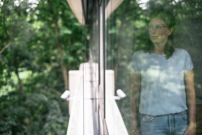 Frau guckt aus dem Fenster in die Natur